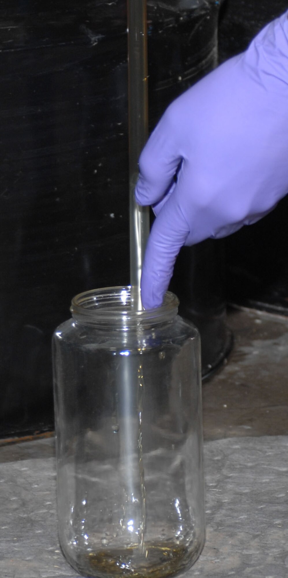 Dyess AFB, Texas - A diesel fuel sample in drained into a container for testing, May 14. Periodically waste is tested to ensure the components are the same and are being disposed of properly. (U.S. Air Force photo by Courtney Richardson)