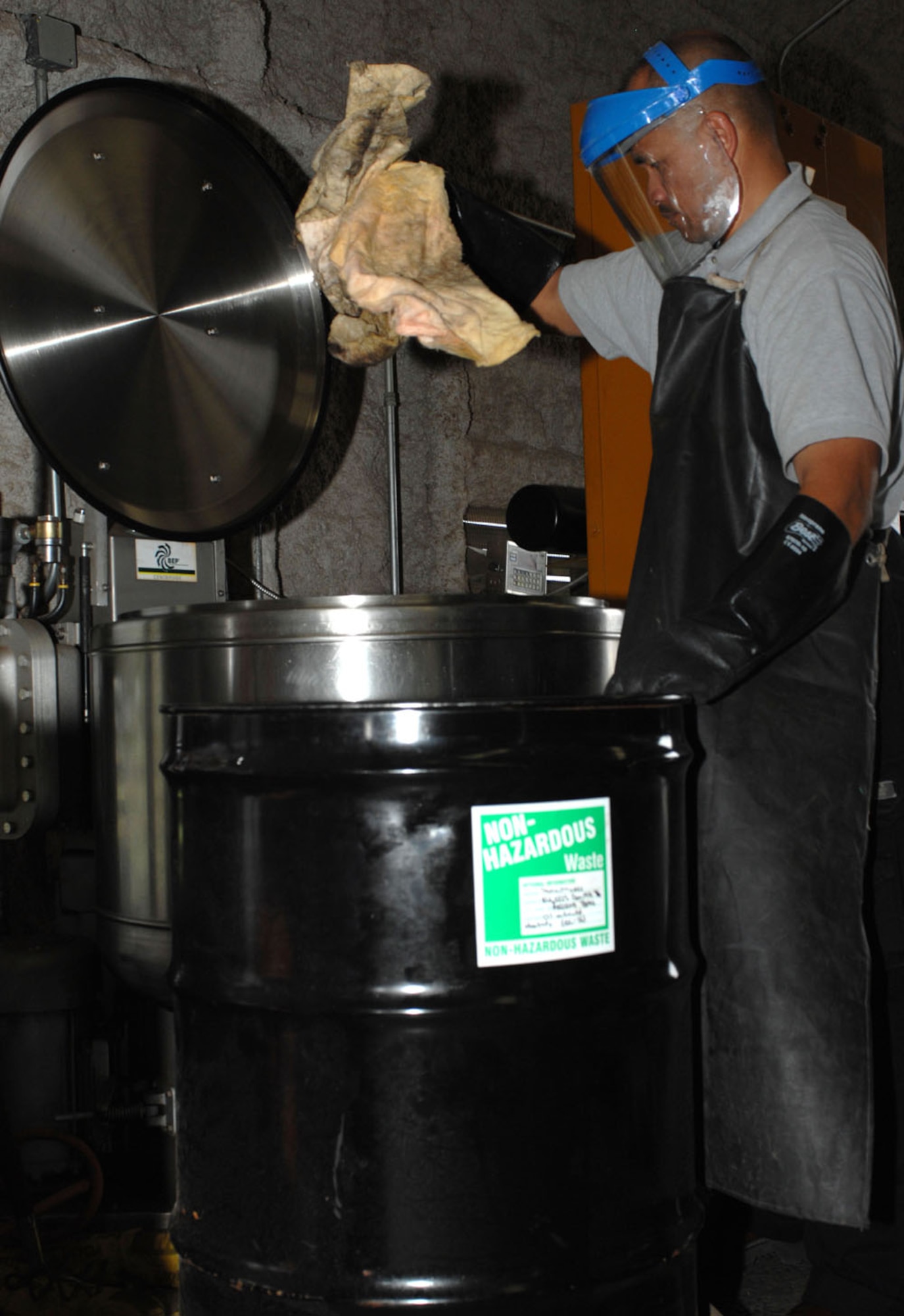 Dyess AFB, Texas - Jesse Diaz, environmental technician,  places absorbent pads, used to clean up spills, into a spinning machine, May 14. The machine is used to spin liquids out of the pad so that they can be used again.(U.S. Air Force photo by Courtney Richardson)