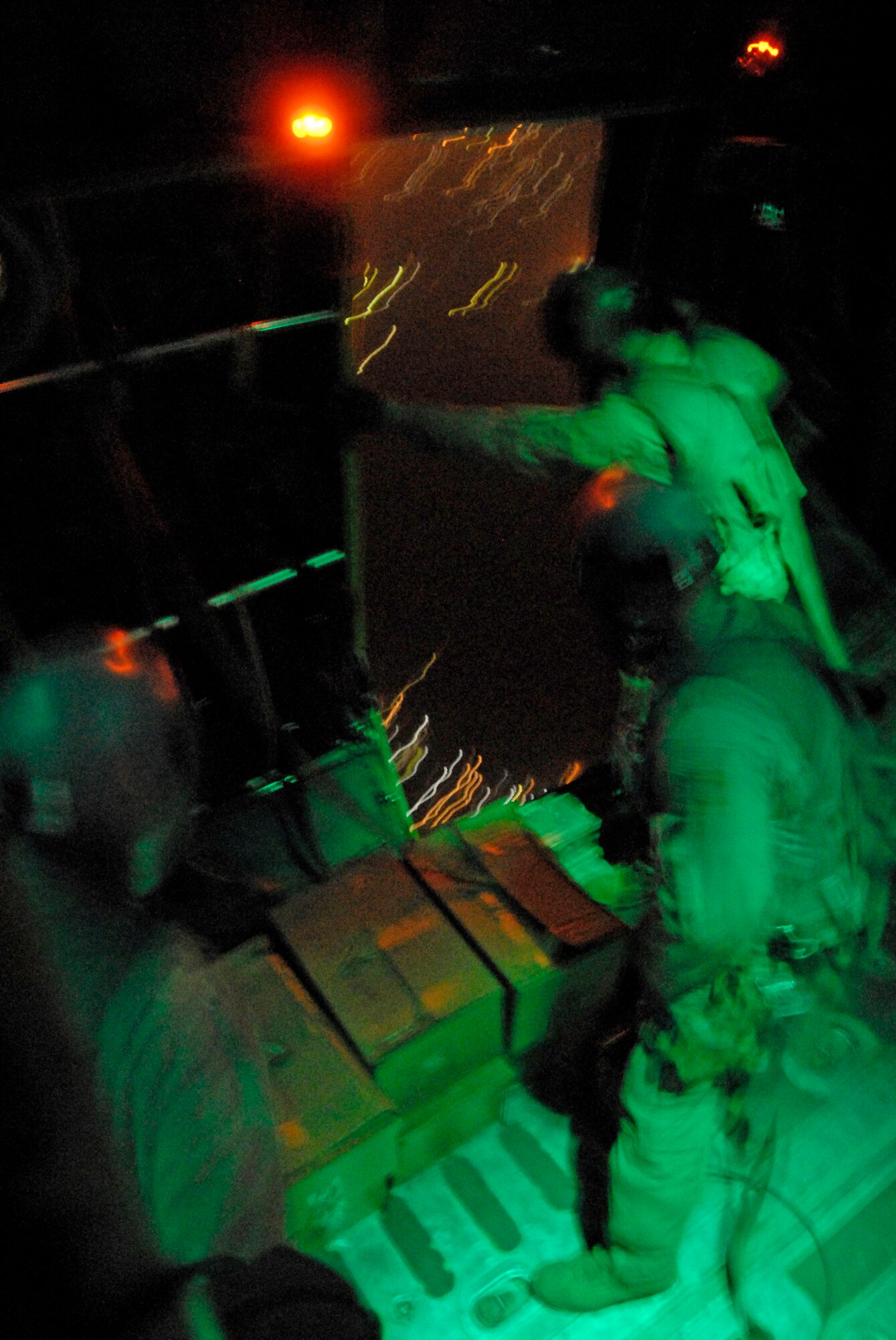 SOUTHWEST ASIA -- Aircrew members from the 737th Expeditionary Airlift Squadron deployed to an air base in the Persian Gulf Region wait for the light above the right rear troop door to turn green before they push out several hundred thousand leaflets over an Iraqi city in May 2008. The three-person team is comprised of 1st Lt. Justin Fitzpatrick (left) and Senior Airman Joel Pfaff (center), who fill the roles as feeders to Staff Sgt. Gabriel Molanders (right), the kicker on the team who ensures the leaflets get out the door and over the target area. All three aircrew members are deployed from Dyess Air Force Base, Texas. (U.S. Air Force photo/Tech. Sgt. Michael O’Connor)