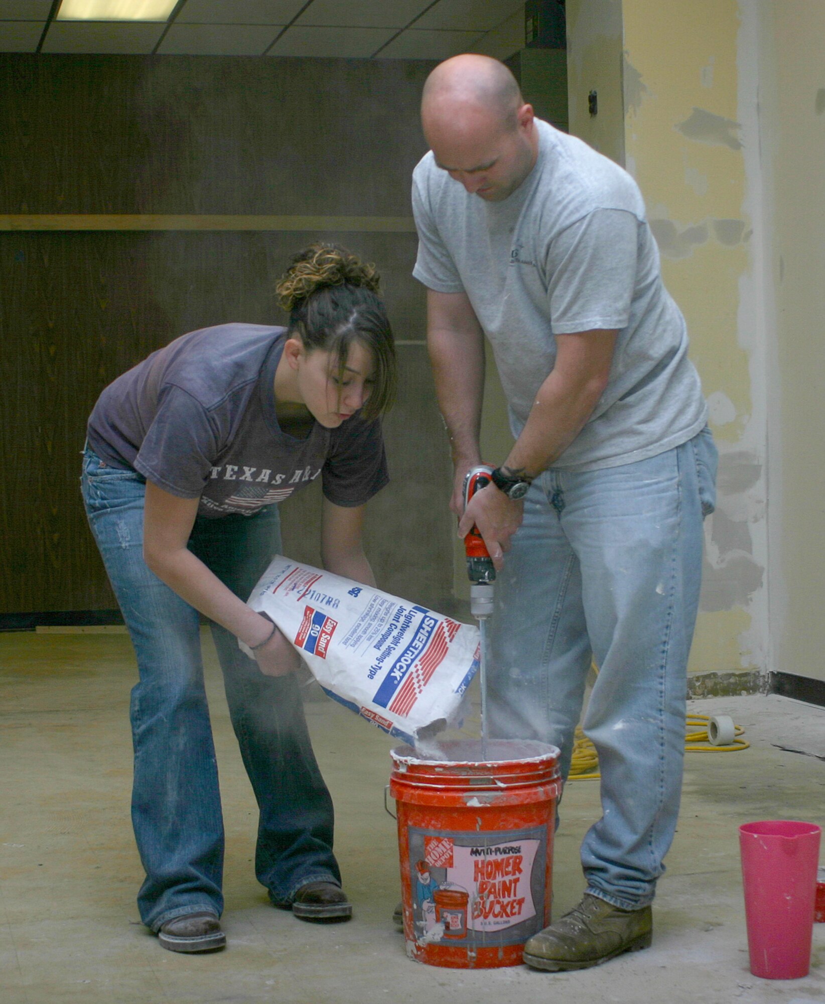 Airman 1st Class Katelyn Chabries, 305th Aircraft Maintenance Squadron, helps Staff Sgt. Francis Gilson, 817th Contingency Response Group, mix sheet rock at the Airman's Attic May 13. Work began on the Attic May 7 and is expected to be completed May 19. Volunteers from squadrons around base and the McGuire 56 have knocked down walls, built others and are now preparing the walls for paint. The Airman's Attic provides Airmen  basic necessities like children's clothes and toys as well as household items. All items are donated by fellow Airmen on base. For more information, contact the Airman and Family Readiness Center at (609) 754-3154. (U.S. Air Force photo/Senior Airman Danielle Johnson)