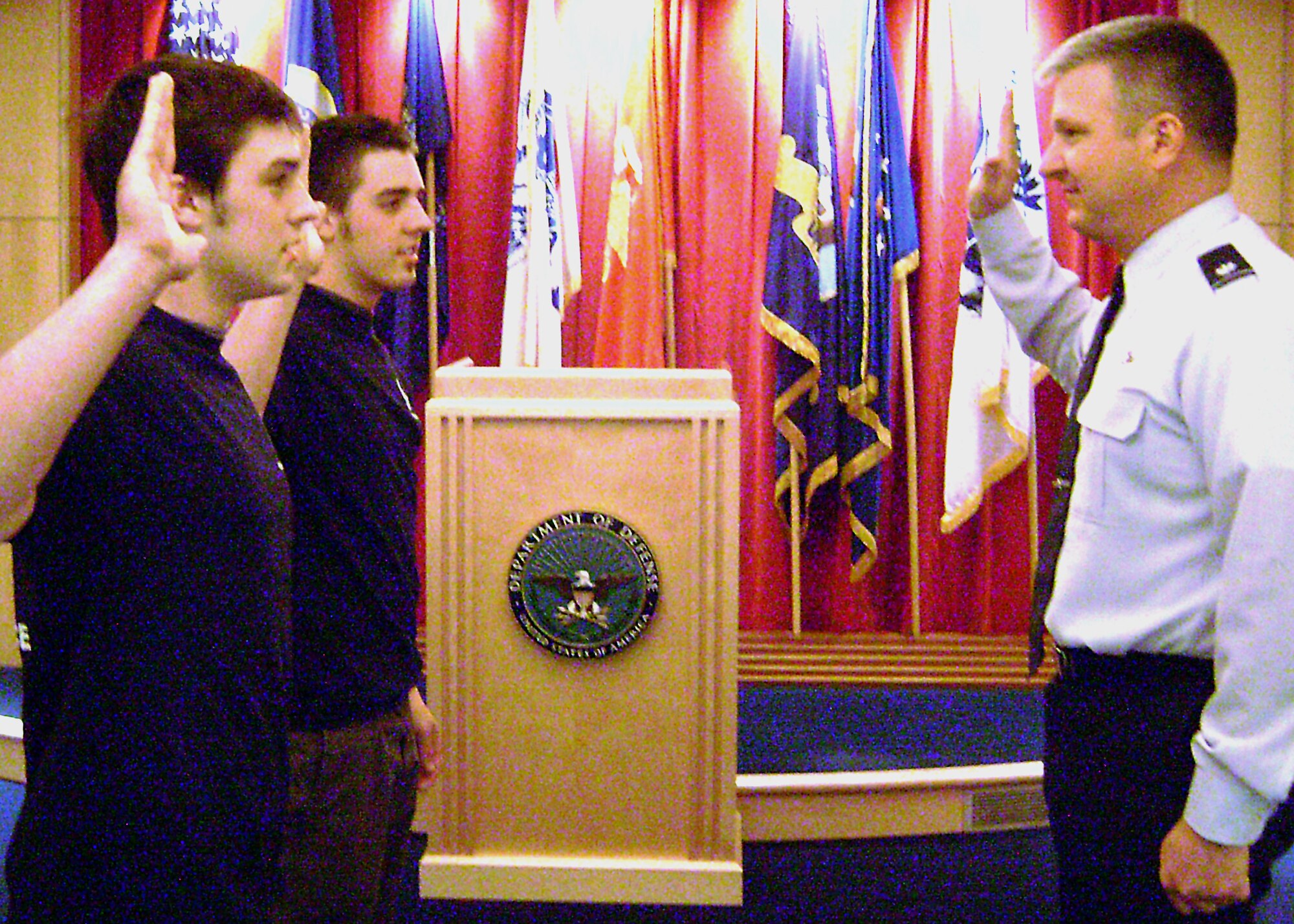 Joel and Erik Bakke of Burnsville, Minn., simultaneously recite the Air Force Oath of Enlistment May 9 at the Minneapolis Military Entrance Processing Station. Lt. Col. Doug Stropes, 342nd Recruiting Squadron commander, delivers the oath for the ceremony.                          