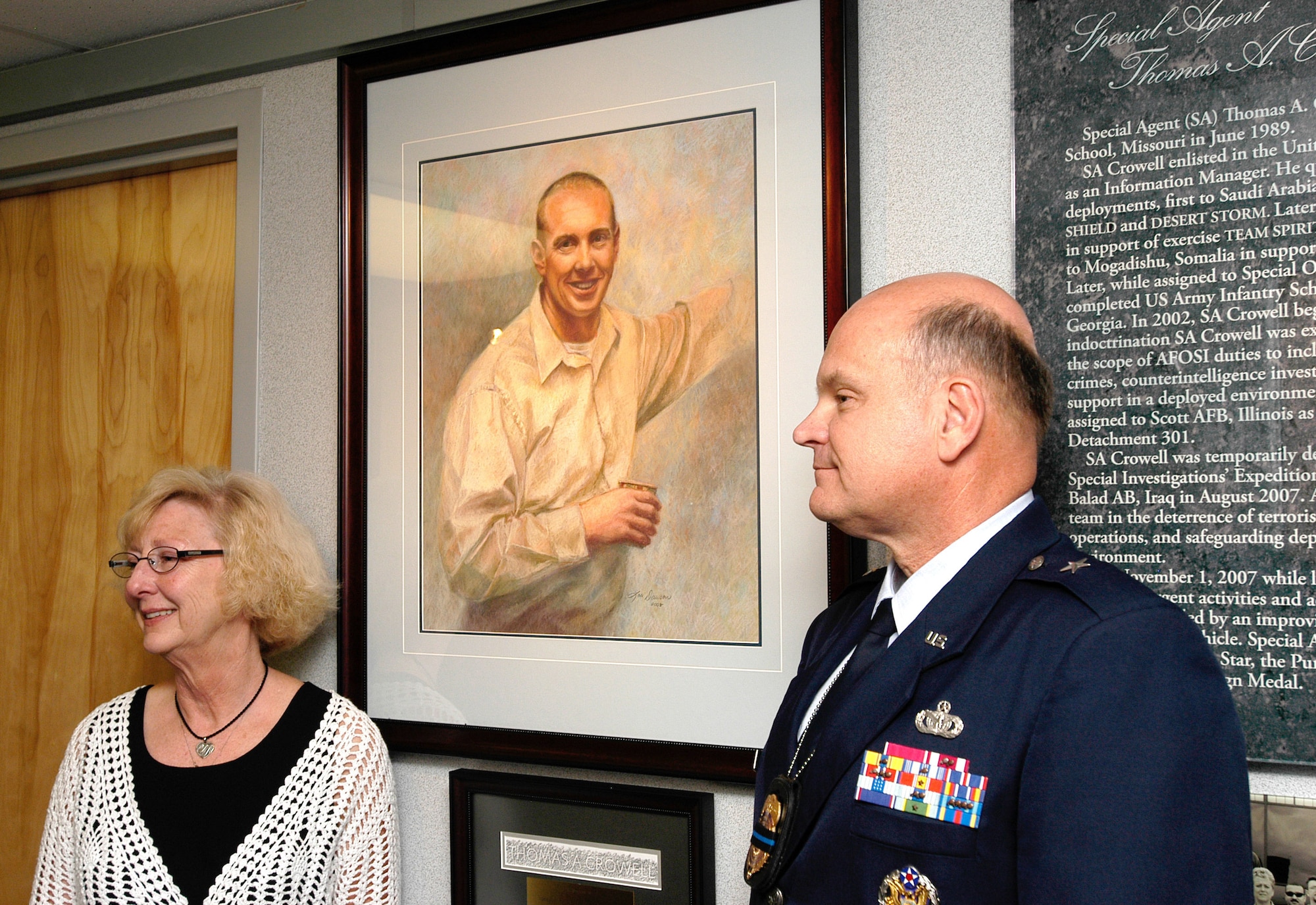 Brigadier General Dana Simmons, commander, Air Force Office of Special Investigations, tours the AFOSI Hall of Heroes with a family member of Special Agent Thomas Crowell. (U.S. Air Force photo/Tech. Sgt. John Jung)