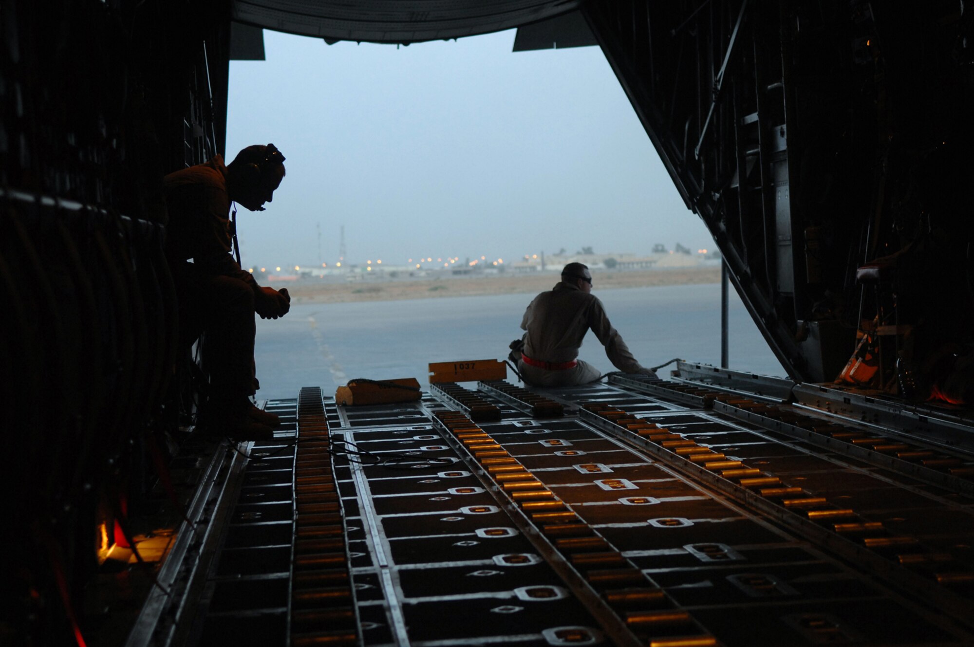 BALAD AIR BASE, Iraq -- Airman 1st Class Nicholas Ellwood and Staff Sgt. Ronnie James, 777th Expeditionary Airlift Squadron loadmasters, wait for cargo and passengers to be loaded onto a C-130 Hercules during a combat mission in Southwest Asia, May 7. The 777 EAS personnel estimate they have prevented approximately 10,000 convoy vehicles and about 27,000 servicemembers from traveling along improvised explosive device laden Iraqi roads since the squadron stood up in January 2006. This was accomplished by providing air transport via C-130 aircraft, the 'work horse' of the Air Force fleet. Airman Ellwood and Sergeant James are deployed from Little Rock Air Force Base, Ark. (U.S. Air Force photo/ Senior Airman Julianne Showalter)