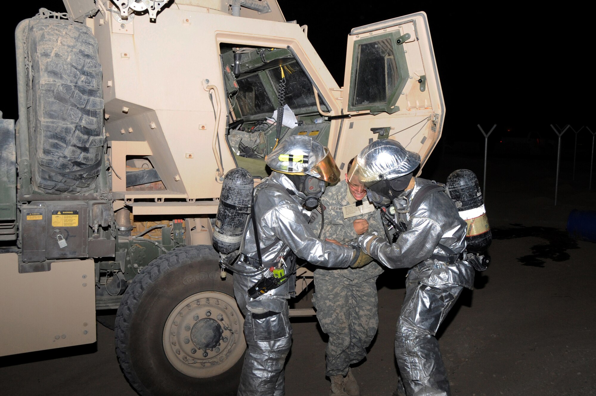 ALI BASE, Iraq -- Staff Sgt. Jason Whalen and Senior Airman John Foxx, 407th Expeditionary Civil Engineering Squadron firefighters, rescue Specialist Kaylob Leathers, member of the HHC 1-82nd Airborne Brigade, from a vehicle involved in a simulated chemical spill during an exercise here May 13.  Air Force Airmen train together with Army Soldiers to share essential skills and knowledge in the case of an incident on Contingency Operating Base Adder and Ali Base.  Sergeant Whalen is deployed from the Nebraska Air National Guard, Airman Foxx is deployed from Mountain Home AFB, Idaho and Specialist Leathers is deployed from Fort Bragg, N.C.  (U. S. Air Force photo / Tech. Sgt. Sabrina Johnson)