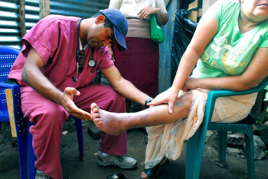 Dr. Miguel Coello examines the leg of a Salvadoran woman at her home, May 8, 2008. The woman  was unable to walk to the school near Comasagua, El Salvador, where free medical care was offered during Fuerzas Aliadas Humanitarias 2008, a medical exercise sponsoredy by the U.S. Southern Command and Salvadoran Ministry of Defense. Dr. Coello is Joint Task Force-Bravo's medical liaison officer.