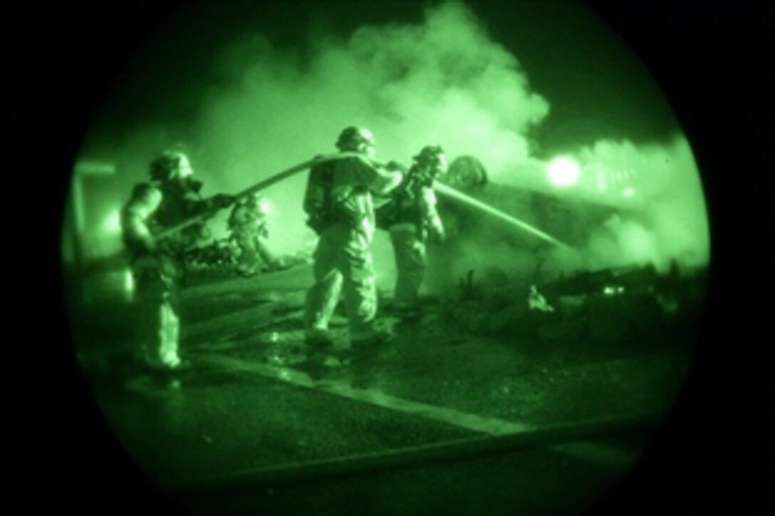 While looking through night vision gear, U.S. Marine firefighters put out a fire in front of the old Gunner’s Gym, May 6, 2008, during a simulated terrorist bombing on Camp Foster, Okinawa, Japan.