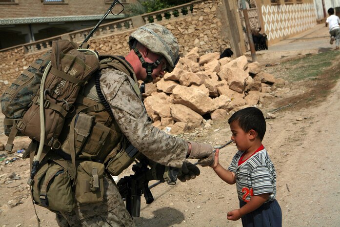 Lance Cpl. Bobby J. Jordan, 20, rifleman with Company K, 3rd Battalion, 4th Marine Regiment, Regimental Combat Team 5, from Tyler, Texas, shakes hands with an Iraqi child during a census patrol May 21. Marines with Company K patrolled through the city of Bani Dahir, Iraq, to questions the local populace. Marines said the communityâ??s sentiment towards Marines and the Iraqi Police was positive.