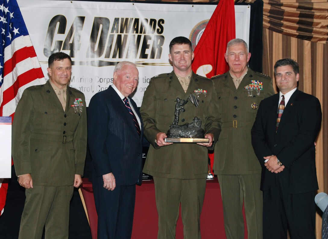 Capt. Thomas J. Cleaver (center), operations officer for 8th Communications Battalion, II Marine Expeditionary Force, holds the Alfred M. Gray trophy at the Marine Corps Association’s annual Command, Control, Communications and Computers Awards Dinner, in Arlington, Va., May 14.  Cleaver received the trophy for his exemplary performance as an operations officer with the Marine Air Ground Task Force Communication Detachment while deployed in support of Operation Iraqi Freedom.