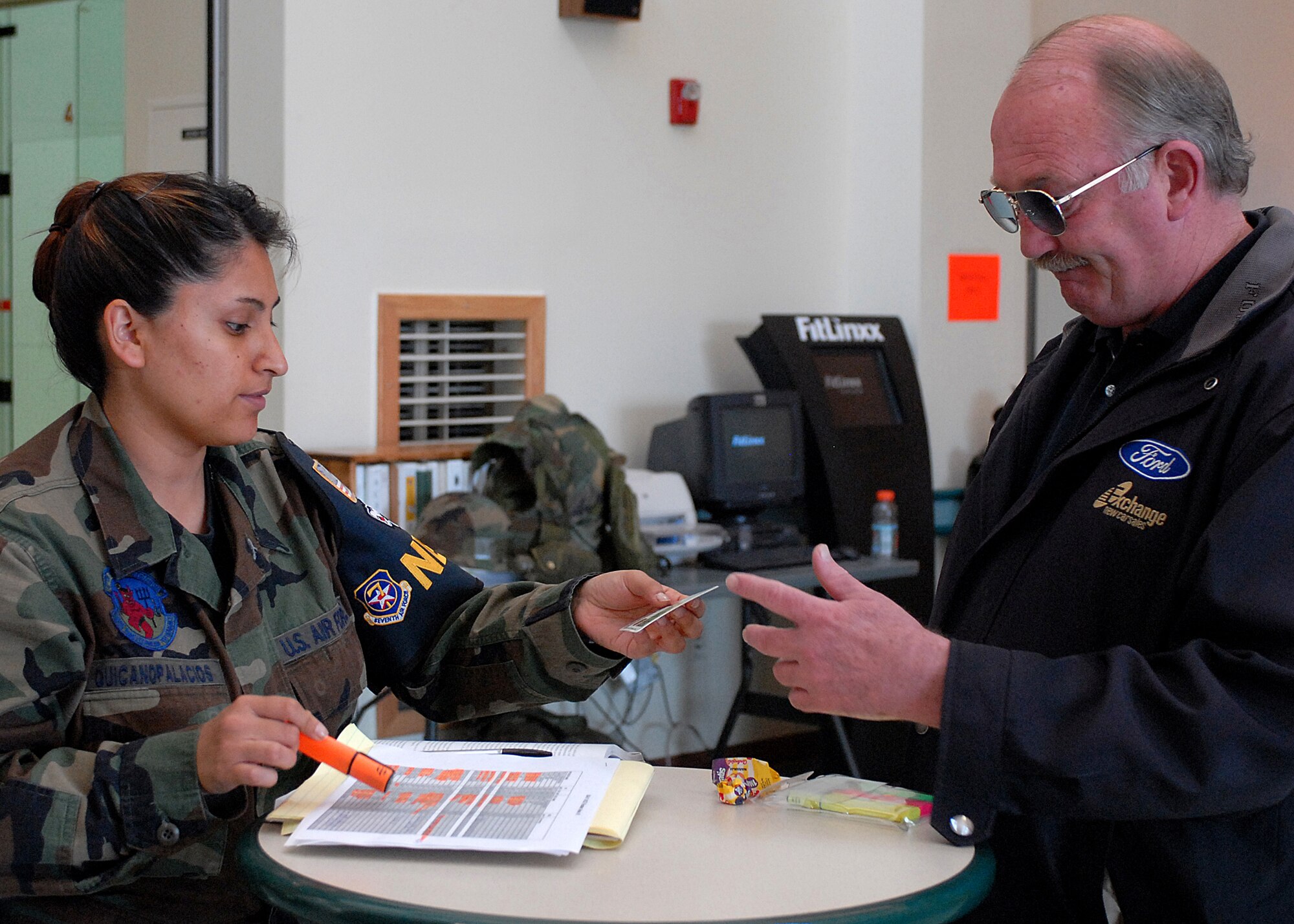 KUNSAN AIR BASE, Republic of Korea --  Technical Sergeant Margie Quincanopalacios from the 8th Civil Engineer Squadron, checks the identification of Mr. John Mullis, new car sales manager, before allowing him to go through the processing line during Courageous Channel here May 16. The Non-combatant Evacuation Operations (NEO), exercise is designed to evacuate Department of Defense (DoD) affiliate civilians in case of emergency events such as natural disasters or war.  The NEO exercise team takes accountability of all DoD civilian personnel, keeps track of their information and transports all their personal household belongings.  (U.S. Air Force photo/Senior Airman Giang Nguyen)