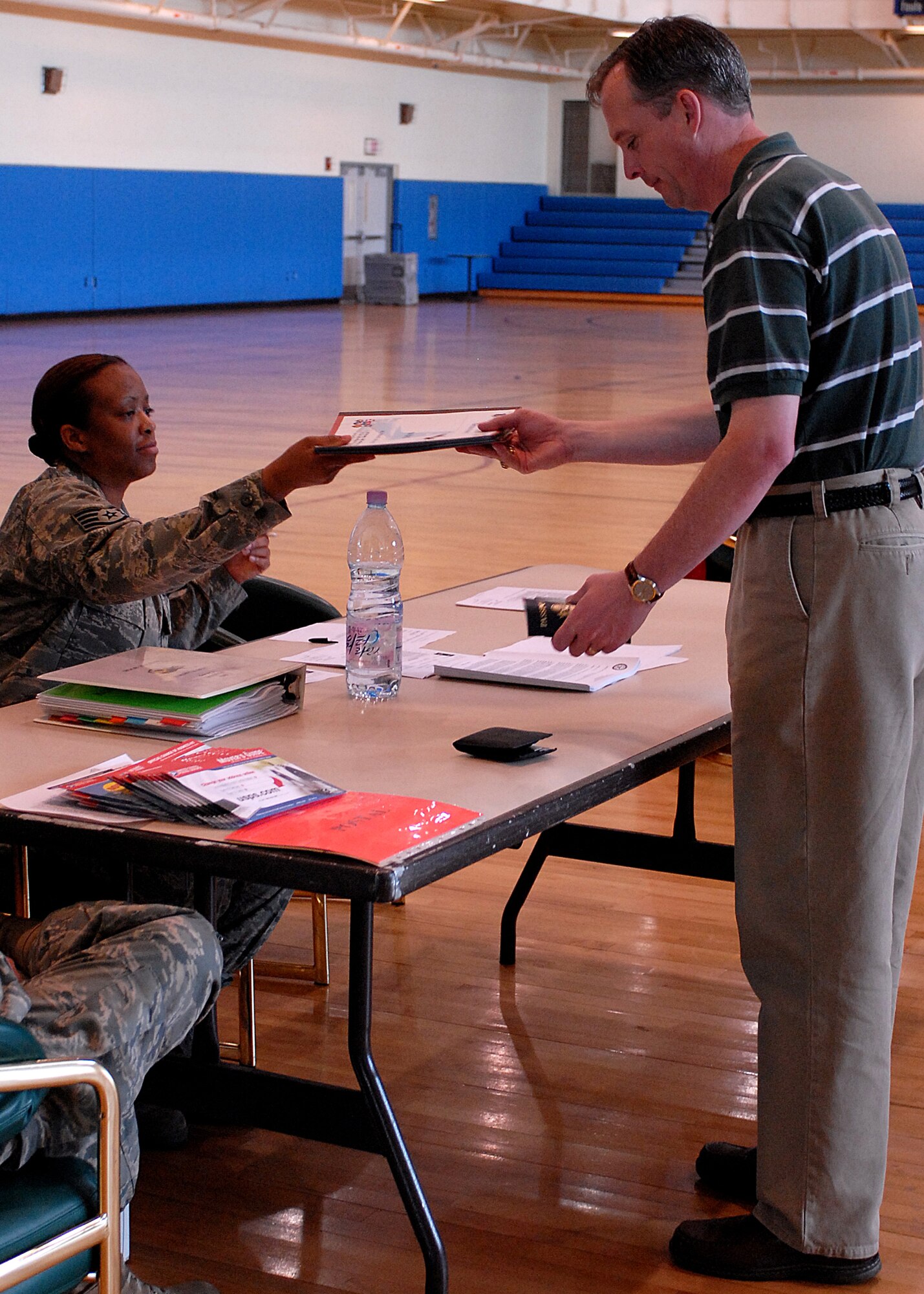 KUNSAN AIR BASE, Republic of Korea -- Staff Sergeant Letrese Lofton, 8th Medical Support Squadron, gives Mr. Todd Wirt, 8th Services Squadron lodging manager his medical documents during Courageous Channel here May 16. The Non-combatant Evacuation Operations (NEO) exercise is designed to evacuate Department of Defense affiliate civilians in case of emergency events such as natural disasters or war.  The NEO exercise team takes accountability of all DoD civilian personnel, keeps track of their information and transports all their personal household belongings.  (U.S. Air Force photo/Senior Airman Giang Nguyen)