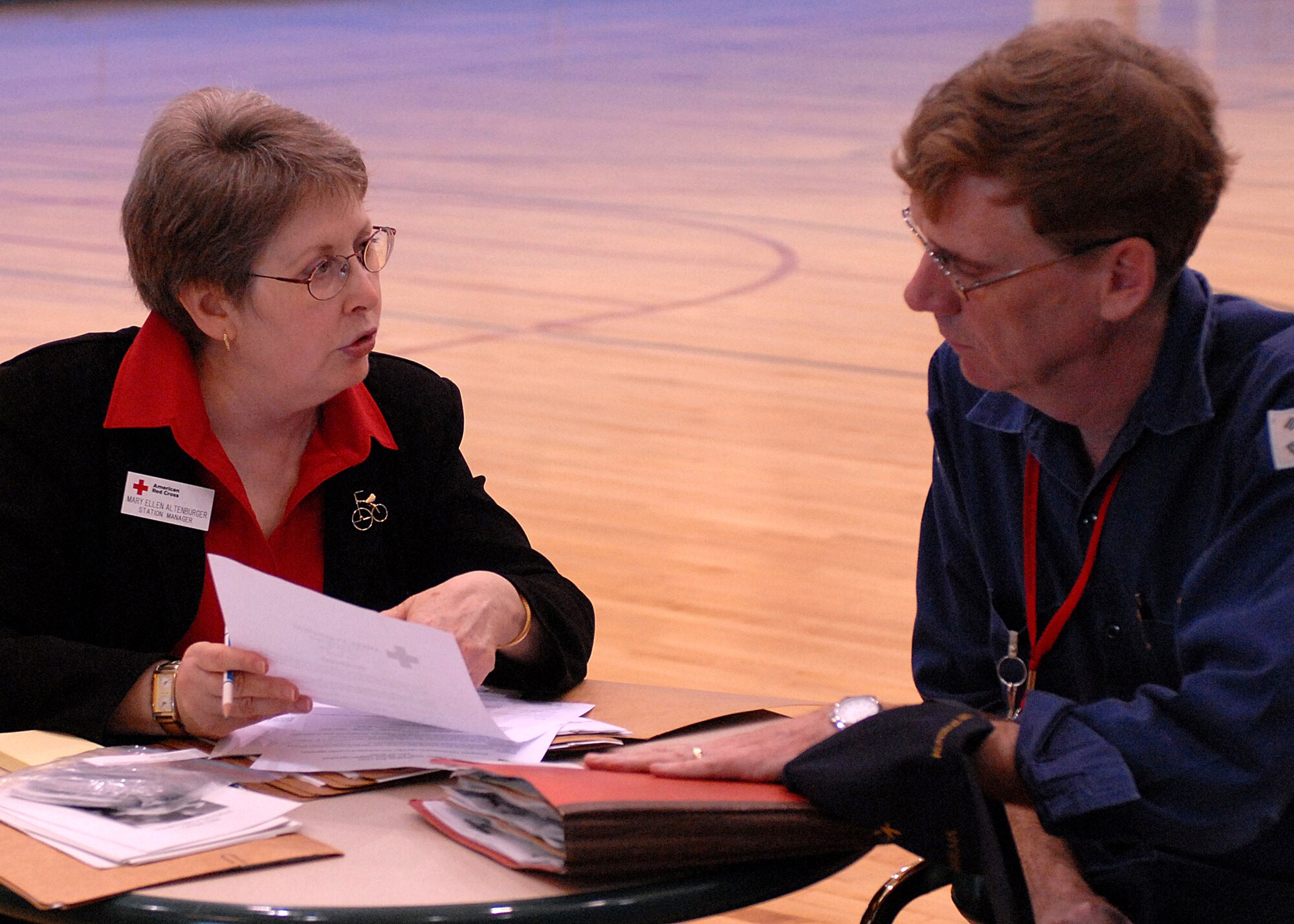 KUNSAN AIR BASE, Republic of Korea -- Mrs. Mary Ellen Altenburger, Red Cross representative, informs Mr. Leonard Greeder, 8th Civil Engineer Squadron mechanical engineer and resource efficiency manager, about Red Cross services during Courageous Channel here May 16.  The Non-combatant Evacuation Operations (NEO) excercise is designed to evacuate Department of Defense affiliate civilians in case of emergency events such as natural disasters or war.  The NEO exercise team takes accountability of all DoD civilian personnel, keeps track of their information and transports all their personal household belongings.  (U.S. Air Force photo/Senior Airman Giang Nguyen)