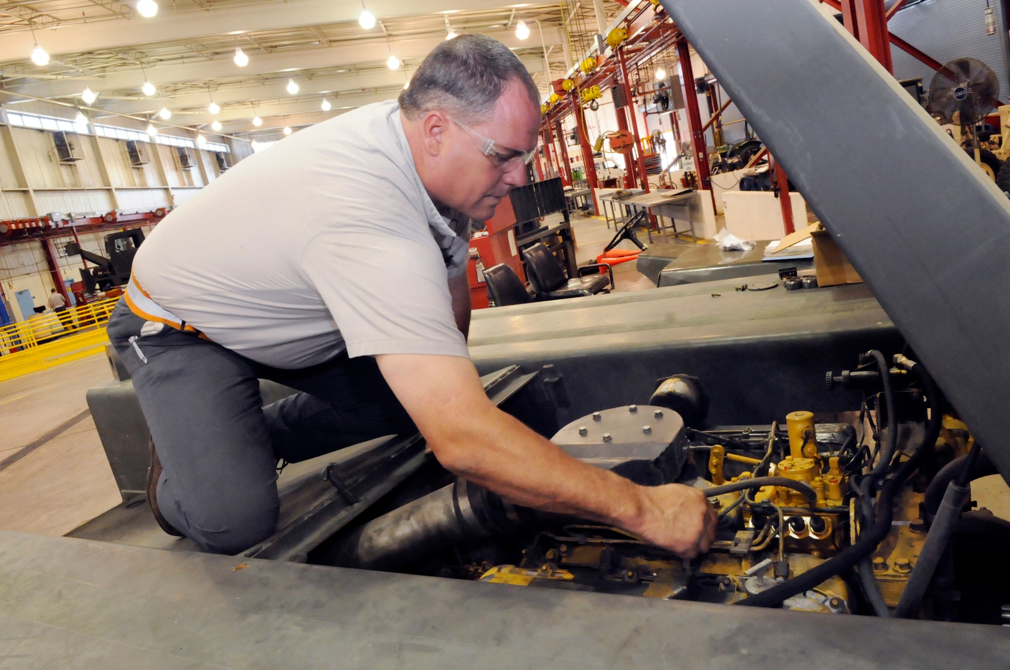 David Langston, master certified mechanic, works on the engine of a MB2 tow tractor in the vehicle maintenance shop. U. S. Air Force photo by Sue Sapp