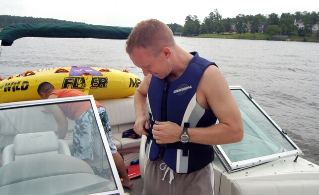 Capt. Jason Knab fastens on a life vest before boating on Lake Tobesofkee last summer as a reminder to practice commonsense safety tips when participating in water activities. 