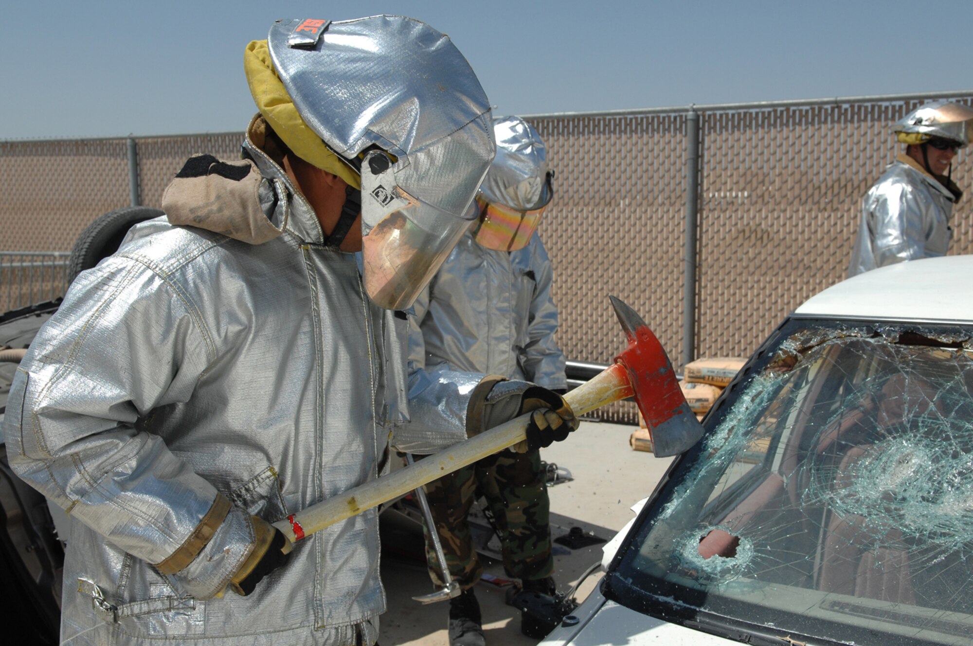 NELLIS AIR FORCE BASE, Nev.—A firefighter from the 99th Civil Engineer Squadron uses an axe to cut and remove a windshield during an auto extrication training class here May 8. Nellis firefighters conduct training every shift to prepare them for potential scenarios they may face on the job such as confined-space rescue and rescuing victims from burning vehicles. (U.S. Air Force photo/Senior Airman Kasabyan D. Musal)