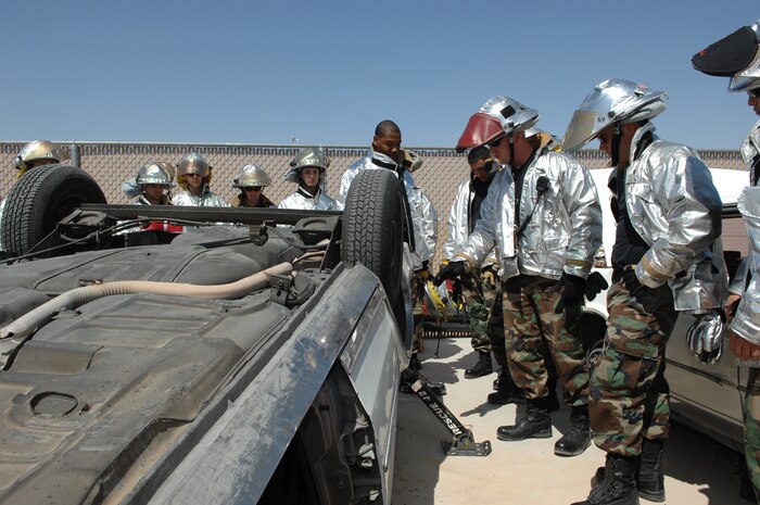 NELLIS AIR FORCE BASE, Nev.— Firefighters from the 99th Civil Engineer Squadron learn how to lift a car using the Rescue 42 jack during their auto extrication training class here May 8. Nellis firefighters conduct training every shift to prepare them for potential scenarios they may face on the job such as confined-space rescue and rescuing victims from burning vehicles. (U.S. Air Force photo/Senior Airman Kasabyan D. Musal) 