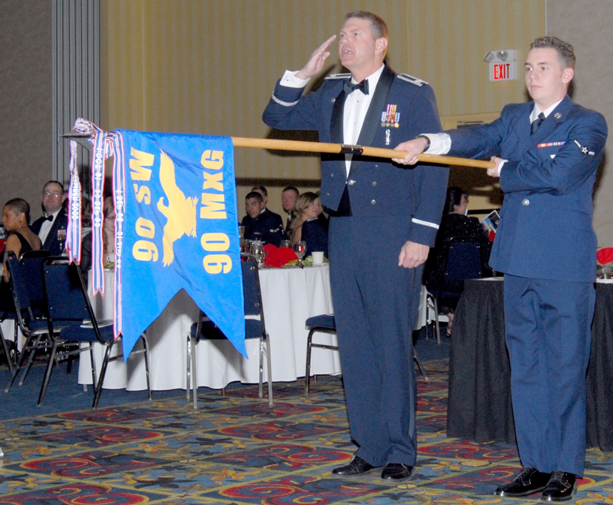 Col. L.B. Mobley, 90th Maintenance Group commander, and Airman James Willis, 90th Maintenance Operations Squadron, present the 90th MXG guidon May 3 to the dining-out president, Col. Mike Morgan, 90th Space Wing commander, signifying their group is present. The dining-out is a tradition-filled event where true Air Force pomp and circumstance is displayed. People committing infractions to the rules of the dining-out are sent to the grog bowl, a container filled with different, unidentified liquids.