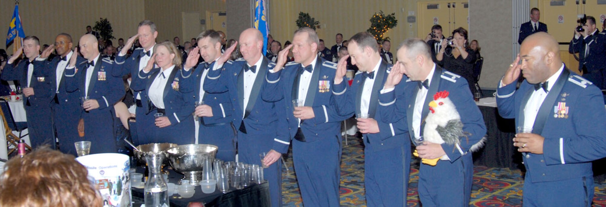 Members of the 90th Operations Group salute the grog before drinking its vile contents. Col. Craigen Anderson, 90th OG commander, was called to the grog for an infraction, and his subordinates followed to show their support.