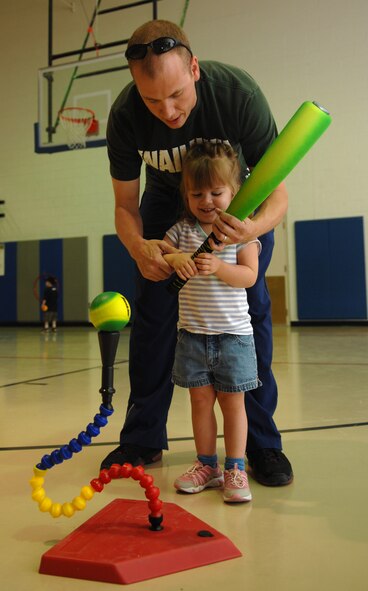 HOLLOMAN AIR FORCE BASE, N.M. -- Georgia Porter, 3, practices hitting a ball off a tee with the assistance of her father, Maj. Maynard Porter, 46th Test Group, at the Youth and Teen Center Holloman Air Force Base, N.M., May 8. Georgia Porter is one of 13 children enrolled in the Start Smart baseball program, which teaches children ages 3 to 5 the fundamentals of baseball before they join an official baseball team. The classes last one hour and are held twice a week for three weeks. All children are accompanied by their parents, who work with them at different stations such as throwing, catching and, in this case, hitting the ball. (U.S. Air Force photo/Airman Sondra M. Wieseler)