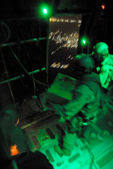 Aircrew members from the 737th Expeditionary Airlift Squadron wait for the light above the right rear troop door to turn green before they push out several hundred thousand leaflets over an Iraqi city recently. The three-person team includes 1st Lt. Justin Fitzpatrick (left) and Senior Airman Joel Pfaff (center), who fill the roles as feeders to Staff Sgt. Gabriel Molanders (right), the kicker on the team who ensures the leaflets get out the door and over the target area. All three aircrew members are deployed from Dyess Air Force Base, Texas. (U.S. Air Force photo/Tech. Sgt. Michael O'Connor) 
