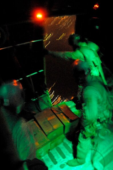 Aircrew members from the 737th Expeditionary Airlift Squadron wait for the light above the right rear troop door to turn green before they push out several hundred thousand leaflets over an Iraqi city recently. The three-person team includes 1st Lt. Justin Fitzpatrick (left) and Senior Airman Joel Pfaff (center), who fill the roles as feeders to Staff Sgt. Gabriel Molanders (right), the kicker on the team who ensures the leaflets get out the door and over the target area. All three aircrew members are deployed from Dyess Air Force Base, Texas. (U.S. Air Force photo/Tech. Sgt. Michael O'Connor) 

