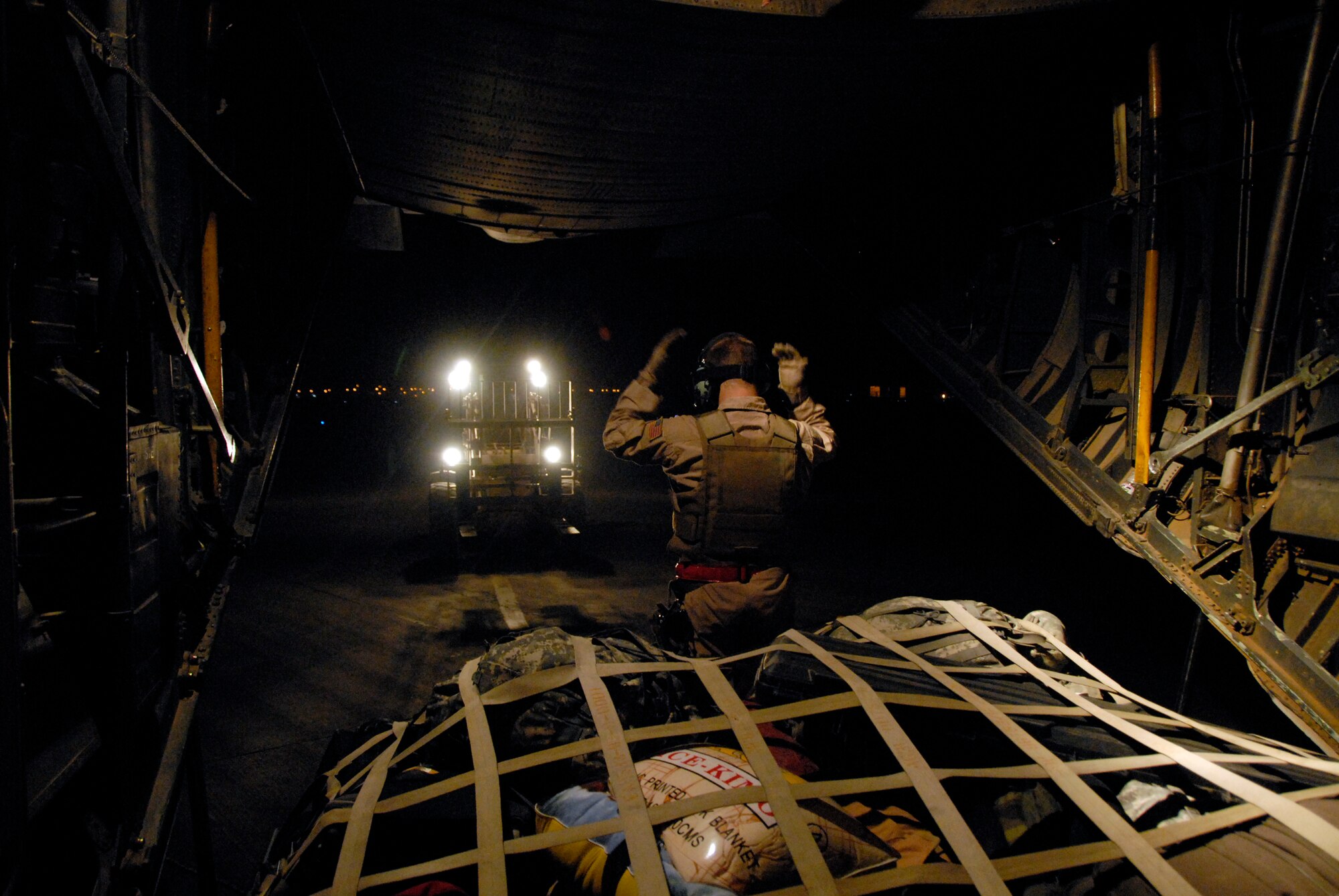 SOUTHWEST ASIA -- Senior Airman Joel Pfaff, a C-130 Hercules loadmaster with the 737th Expeditionary Airlift Squadron, martials in Airman 1st Class Bryan Rogers, an aerial porter from the 447th Air Expeditionary Group during a passenger and cargo download/upload mission at an air base in Iraq May 13, 2008. Airman Pfaff is deployed from Dyess Air Force Base, Texas, and Airman Rogers is deployed from McGuire AFB, N.J. (U.S. Air Force photo/Tech. Sgt. Michael O'Connor)