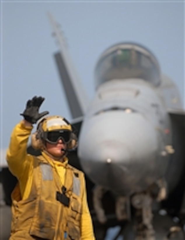 A U.S. Navy aircraft director signals to a tractor driver during flight operations aboard the Nimitz-class aircraft carrier USS Abraham Lincoln (CVN 72) while underway in the Persian Gulf on May 13, 2008.  The Lincoln is deployed to the U.S. Navy 5th Fleet area of responsibility to support maritime security operations.  