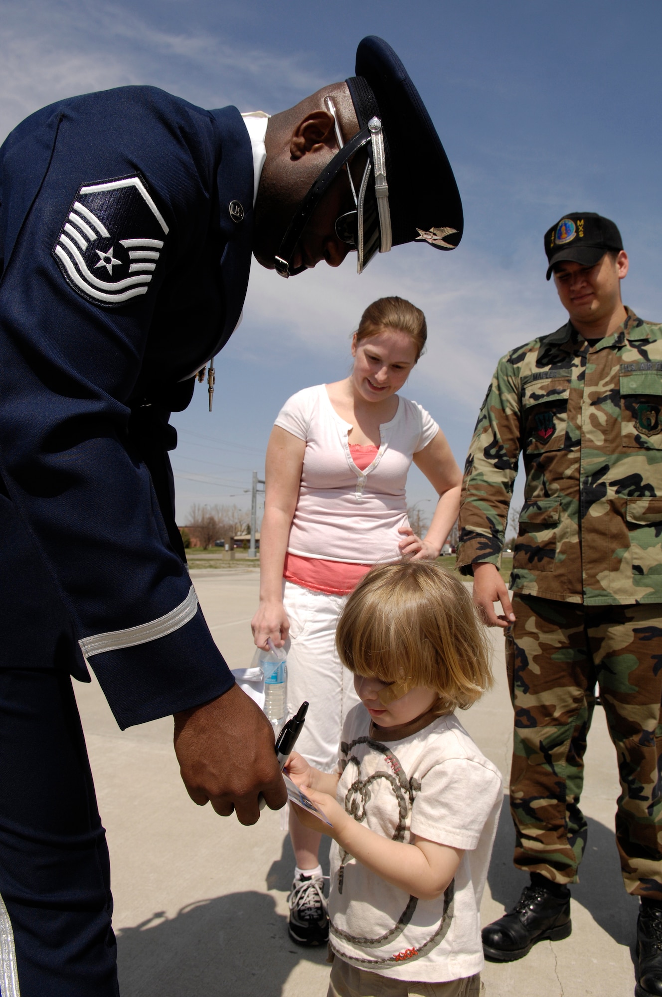 Master Sgt. Steven West, Drill Team Superintendent, writes a message for a child after the team's performance at Minot AFB.  The AF Honor Guard Drill Team is the traveling component of the AF Honor Guard and tours world-wide representing all Airmen and showcasing USAF precision to recruit, retain, and inspire for the Air Force mission. (U.S. Air Force photo by Senior Airman Dan DeCook)(Released)