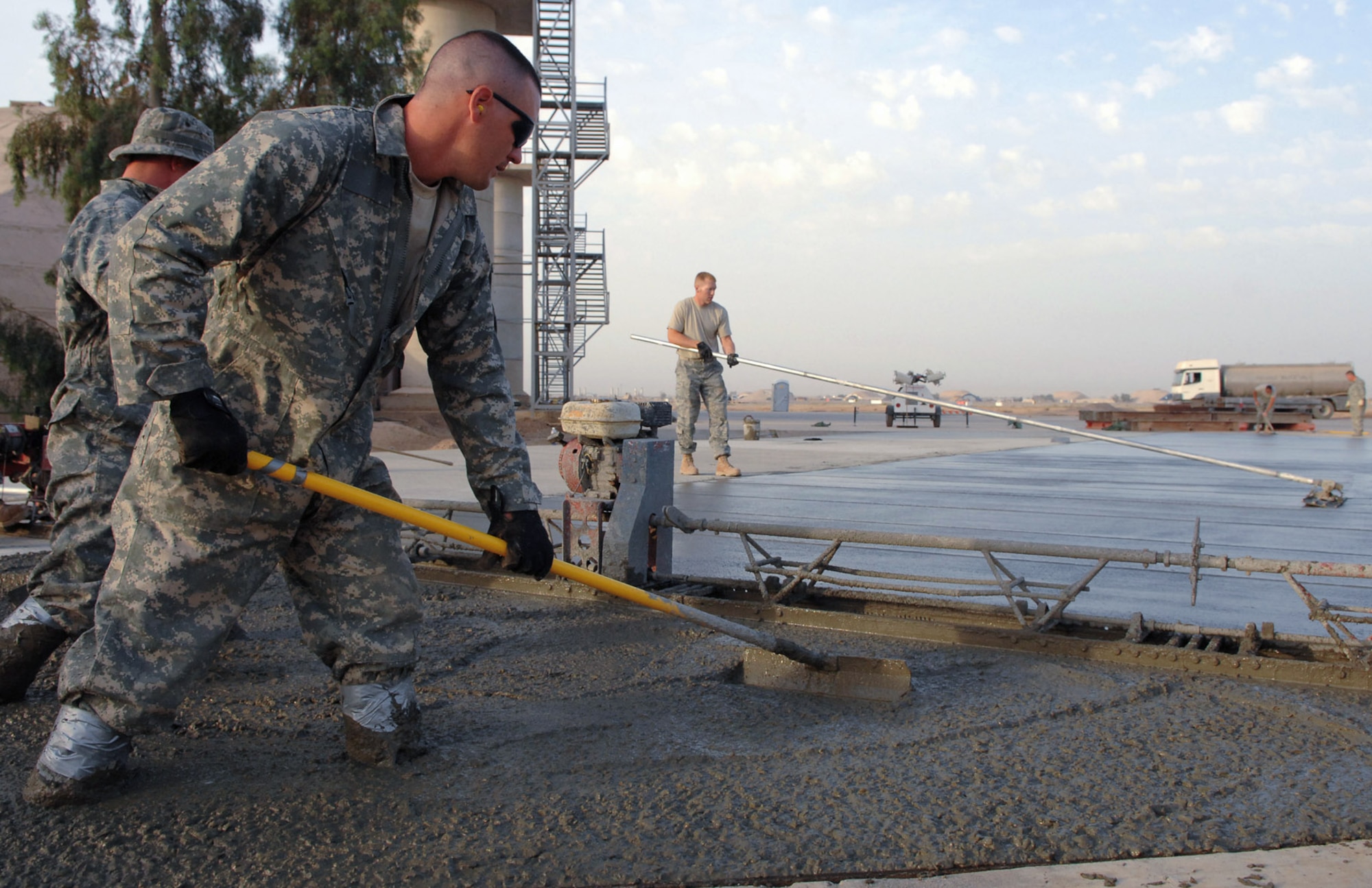 Staff Sgt. Ryan Ward pushes wet concrete around to ensure even dispersion May 13 at Balad Air Base, Iraq. Sergeant Ward is a 332nd Expeditionary Civil Engineer Squadron heavy equipment operator deployed from McConnell Air Force Base, Kan. (U.S. Air Force photo/Senior Airman Julianne Showalter) 
