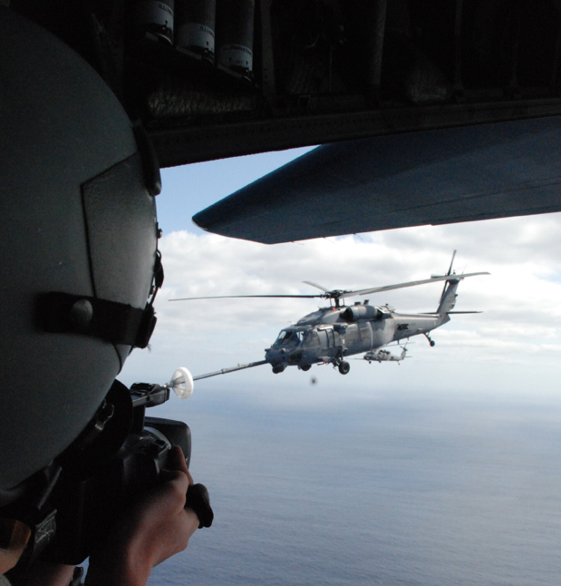 PATRICK AIR FORCE BASE, Fla. -- A civilian videographer takes dynamic footage of a HH-60G Pave Hawk helicopter as it is refueled in mid-air by a HC-130P/N.  The two aircraft were participating in a Mode 8 search and rescue exercise.  The videographer was safely tethered in the HC-130P/N. The purpose of the exercise was to test the capabilities to locate and recover a Space Shuttle astronaut in the event of an open-ocean bailout. (U.S. Air Force photo/Capt. Cathleen Snow) 