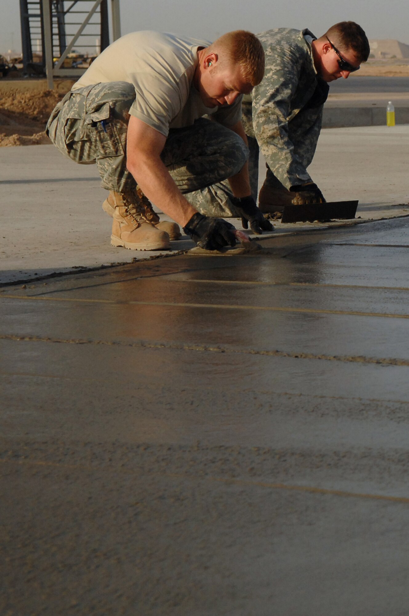 BALAD AIR BASE, Iraq -- Staff Sgts. Rohde Orlin and Ryan Ward, 332nd Expeditionary Civil Engineer Squadron heavy equipment operators, smooth and edge the side of a concrete pad here, May 13. In less than four months, Balad 'Dirt Boyz,' have placed and finished more than 12,460 feet of concrete and added approximately 90,000 square feet of pavement to the airfield. Sergeant Orlin is deployed from Ellsworth Air Force Base, S.D.; and Sergeant Ward is deployed from McConnell Air Force Base, Wash. (U.S. Air Force photo/ Senior Airman Julianne Showalter)