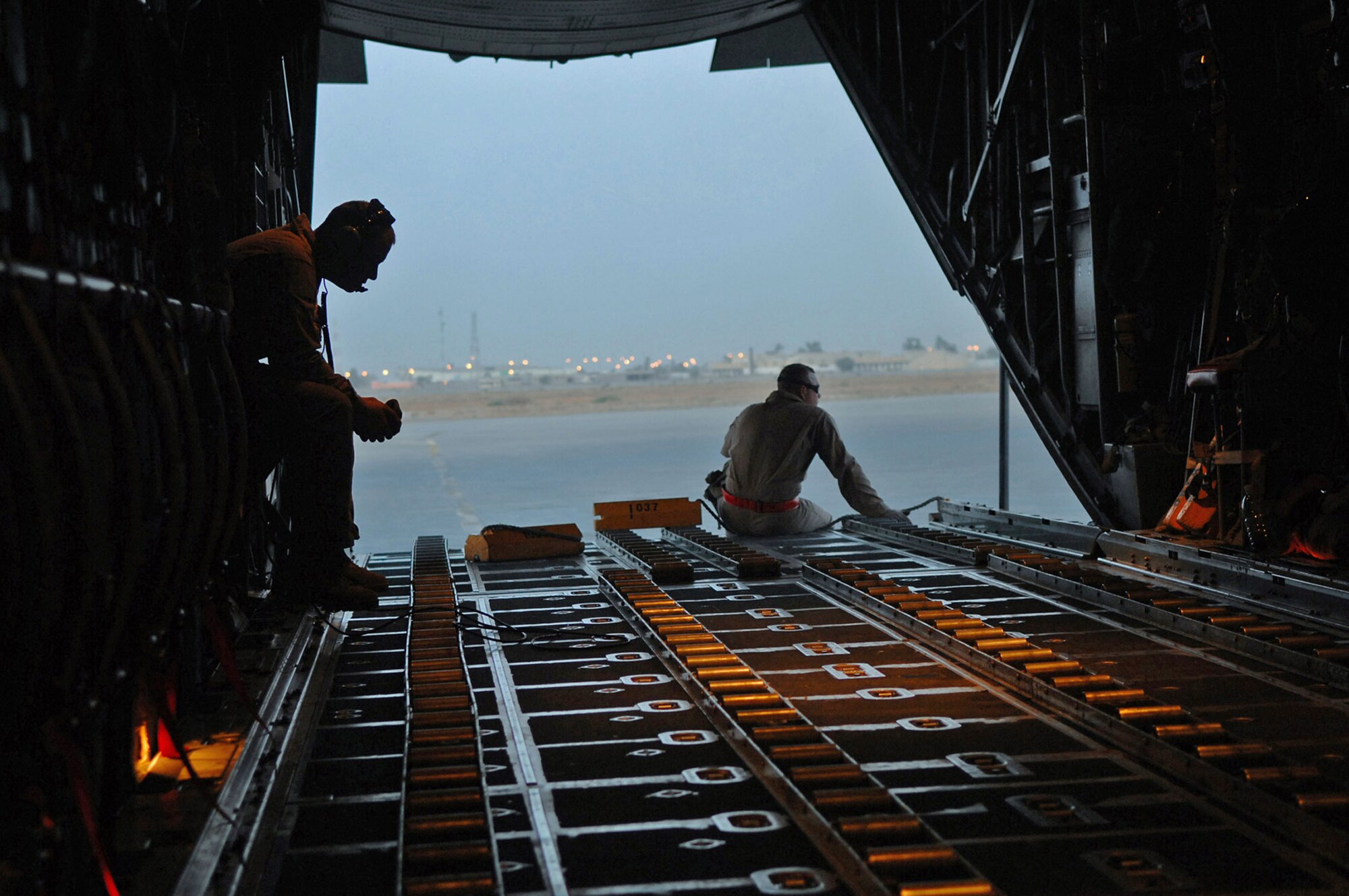 Airman 1st Class Nicholas Ellwood and Staff Sgt. Ronnie James wait for cargo and passengers to be loaded onto a C-130 Hercules during a combat mission May 7 at Balad Air Base, Iraq. Members of the 777th Expeditionary Airlift Squadron help prevented convoy vehicles and servicemembers from traveling along improvised explosive device-laden Iraqi roads by airlifting troops and supplies throughout the area of operations. Airman Ellwood and Sergeant James are 777th EAS loadmasters deployed from Little Rock Air Force Base, Ark. (U.S. Air Force photo/Senior Airman Julianne Showalter) 
