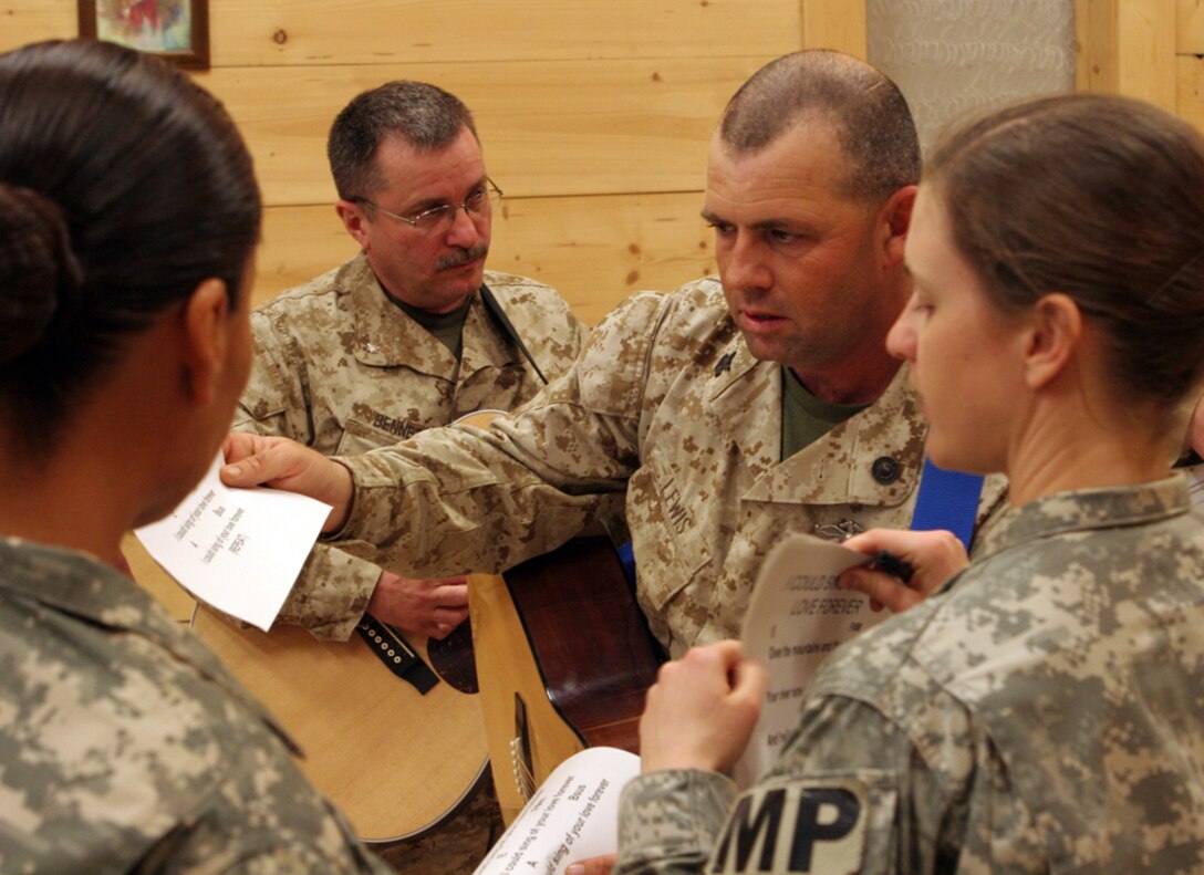 Petty Officer 1st Class Boyd W. Lewis, 41, from Willisburg, Ky., who is a religious programs specialist with Regimental Combat Team 5, reviews the music with the other band members as they get ready to practice some new songs for the service on Sunday at the Camp Ripper chapel on Al Asad Air Base, Iraq, May 19. Lewis used to be in a 'trailer-park punk' band called Bug Eyed Rachel, but is planning on starting his own punk Christian band.