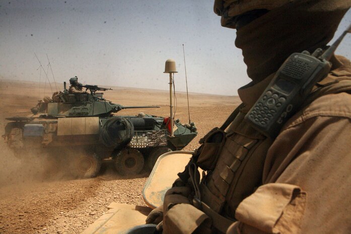 Sgt. Carl J. Woods, 24, a scout team leader from Virginia Beach, Va., with Delta Company, 2nd Light Armored Reconnaissance Battalion, Regimental Combat Team 5, watches on as a light armored vehicle passes during an assembly of an observation post May 18. The Camp Lejeune-based company, known as â??Outlaw,â?? assisted the U.S. Navy SEALS in a raid that yielded a key suspect in Operation Iraqi Freedom.