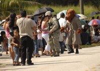 A 36th Security Forces Squadron member and McGruff the Crime Dog hand out candy to families in Inarajan Village during the Malojloj Fiesta May 17.  (U.S. Air Force photo by Staff Sgt. Patrick Mitchell)