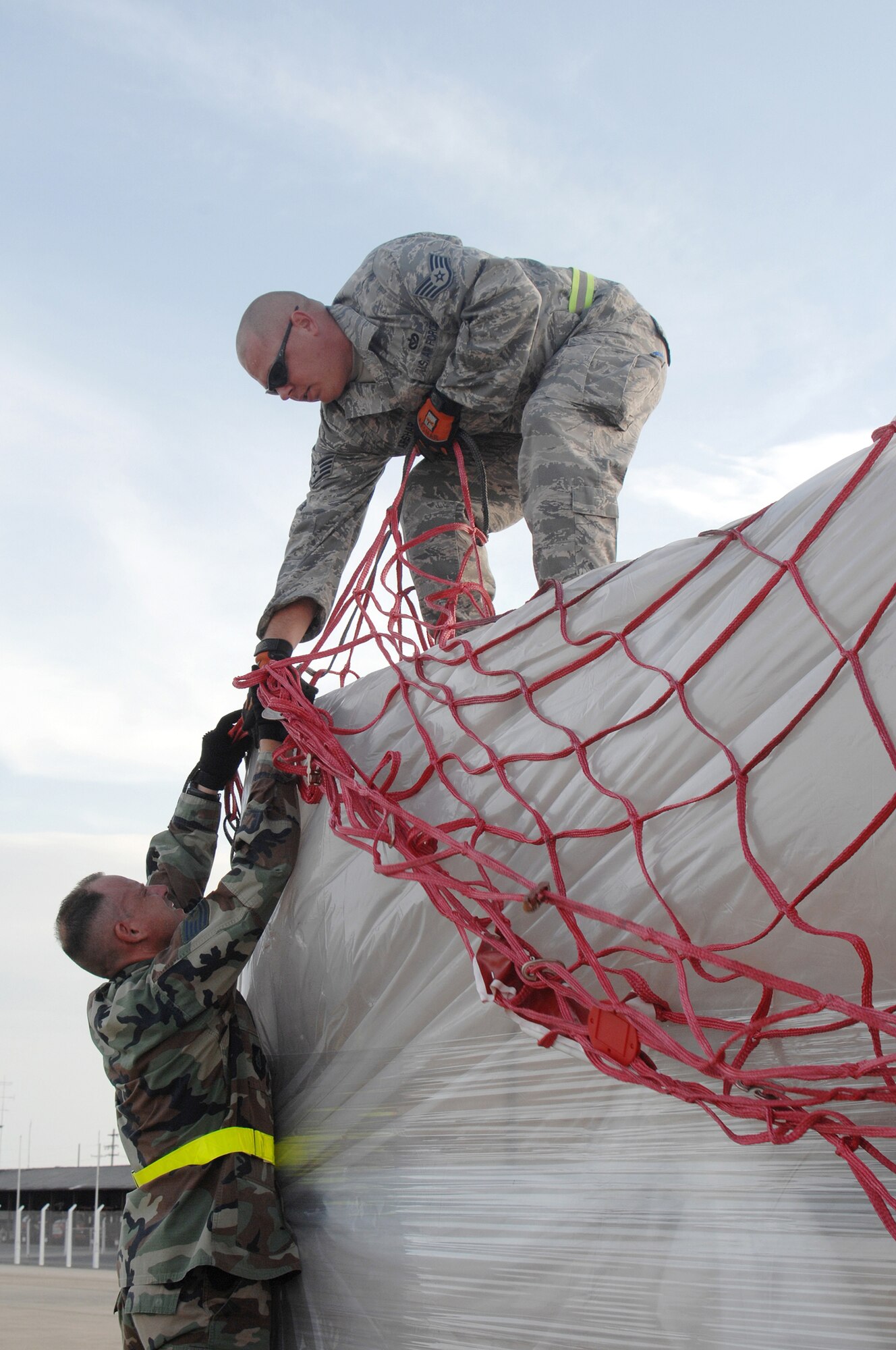 Utapao, Thailand - Technical Sgt John Kortez and Staff Sgt Randy Afshar remove cargo netting from a pallet being downloaded from a Boeing 747 commercial airplane for humanitarian relief efforts to the people of Myanmar May 16. TSgt Kortez is from the 36th Contingency Response Squadron and SSgt Afshar is from the 554 RED HORSE Squadron, both from Andersen AFB, Guam. (USAF photo/Senior Airman Sonya Croston)(RELEASED)
