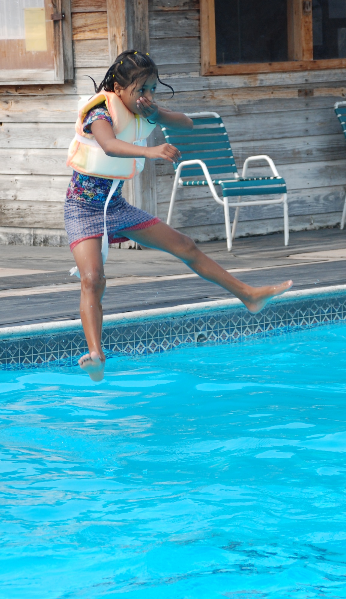 A girl from the Hogar de Guadalupe Orphanage jumps into the pool at Soto Cano Air Base, Honduras, during a kids' day May 18. About 40 volunteers from the 612th Air Base Squadron spent the day playing games and interacting with the children. (U.S. Air Force photo by Tech. Sgt. John Asselin)