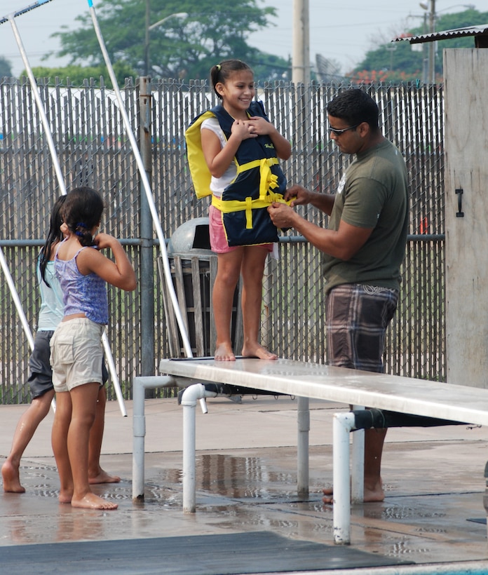 Air Force Staff Sgt. Daniel Santiago, 612th Air Base Squadron civil engineer flight, helps a girl with a life jacket prior to her diving into the pool. More than 100 children and staff from Hogar de Guadalupe Orphanage in El Conejo, Honduras, came to Soto Cano Air Base May 18 for a day of fun and relaxation. (U.S. Air Force photo by Tech. Sgt. John Asselin)
