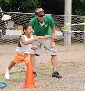 Senior Airman George Schaultz, 612th Air Base Squadron logistics, plays a hoop toss game with a girl from the Hogar de Guadalupe Orphanage during kids' day at Soto Cano Air Base May 18. About 40 volunteers from the 612th ABS came out to make sure the children had a care-free day of fun and activities. (U.S. Air Force photo by Tech. Sgt. John Asselin)