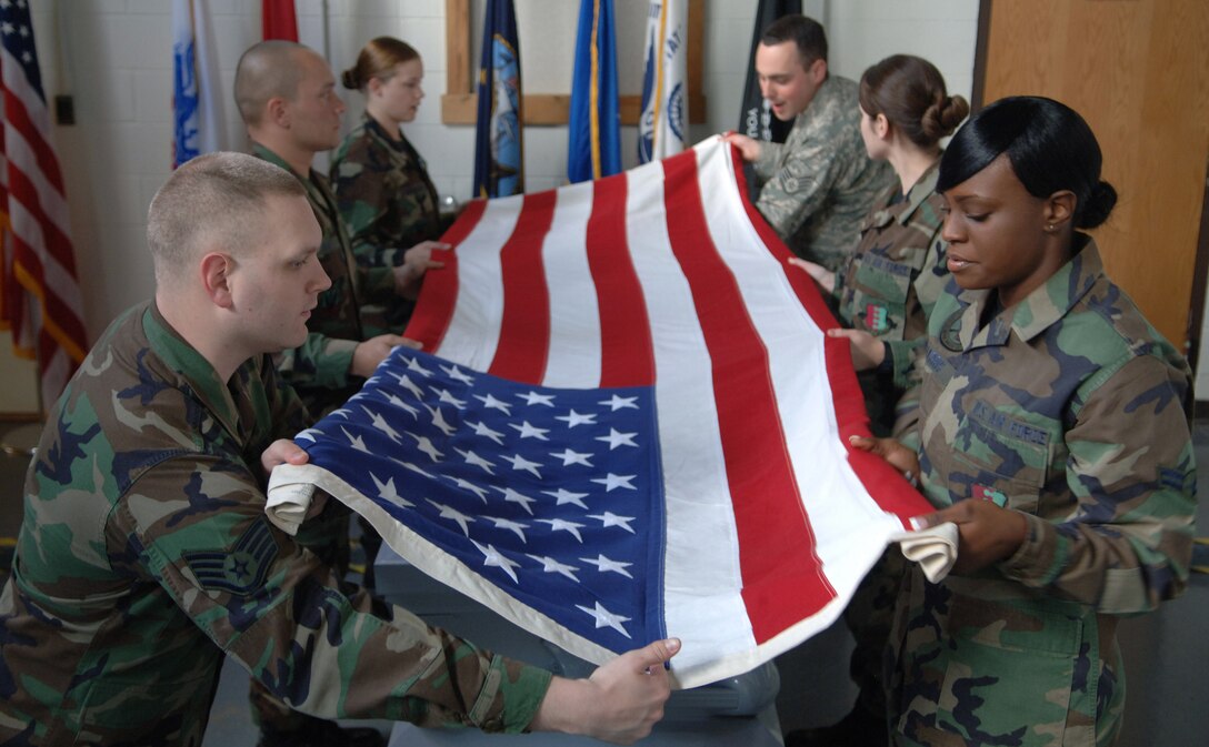 Staff Sgts. Aaron Smith (lower left) and Phillip Campbell (top right), 28th Bomb Wing Honor Guard, instruct honor guard members on how to fold the American flag properly during honor guard practice, May 15.  Honor guard members train weekly to heighten their skills and teamwork.  (U.S. Air Force photo/Airman Corey Hook)(Released)