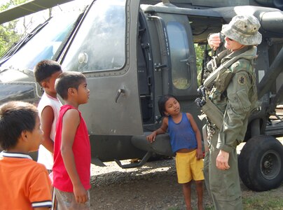 Chief Warrant Officer Kristin Schmid, a UH-60 Blackhawk pilot from Joint Task Force-Bravo, takes a break between lifts to show local Costa Rican children crew equipment and the aircraft. The JTF-Bravo team was in Costa Rica May 9-14 to airlift bridge building materials to three remote areas.