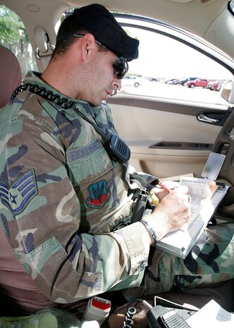 NELLIS AIR FORCE BASE, Nev.—Staff Sgt. Robert Eichenhorst, 99th Security Forces Squadron patrolman, writes a traffic ticket to a motorist for not carrying an insurance card here May 13. The safety and protection of every person on the installation is a vital, visible responsibility for Airmen on patrol. (U.S. Air Force photo/Staff Sgt. Jacob R. McCarthy)