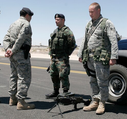 NELLIS AIR FORCE BASE, Nev.—Master Sgt. Carlos Guevara (left), 99th Security Forces Squadron alpha flight commander, conducts a post briefing with Airman 1st Class Jose Alvarez (center)and Senior Airman Matthew Waldron, both 99th SFS patrolmen, while on patrol here May 13. Post briefings give flight commanders hands-on situational awareness during their shift and to keep patrolmen sharp and alert. (U.S. Air Force photo/Staff Sgt. Jacob R. McCarthy)