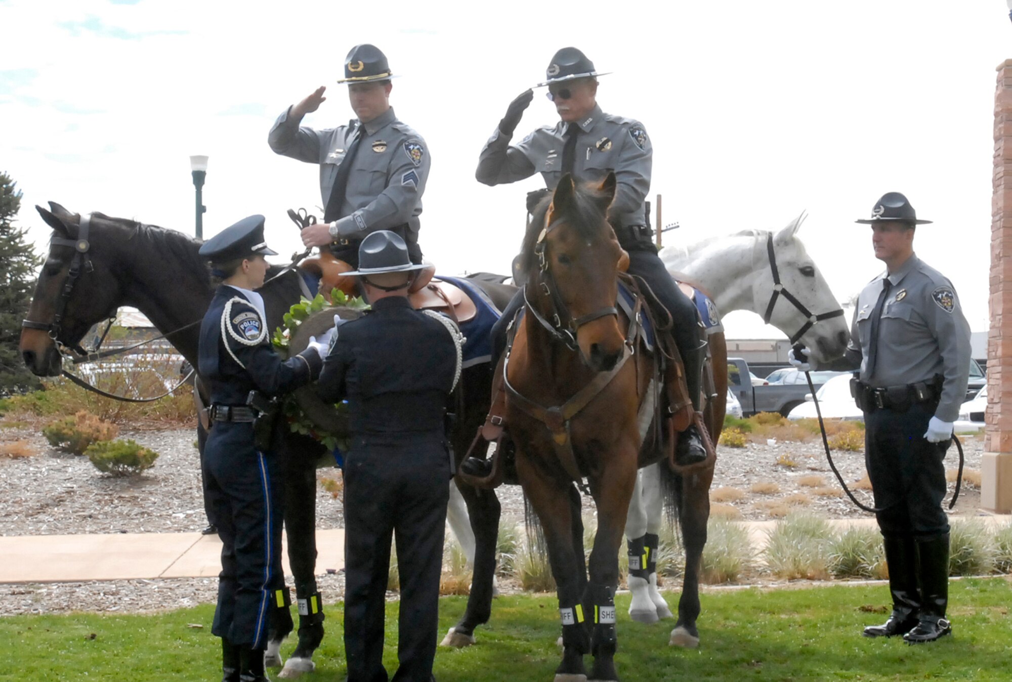 Mounted police officers salute during the presentation of a memorial wreath during the 15th Annual Pikes Peak Region Peace Officer Memorial Day Service May 16 at America the Beautiful Park. Members of the 21st and 721st Security Forces Squadrons were present to honor fellow peace officers who gave their lives while serving their communities. (U.S. Air Force photo/Robb Lingley)