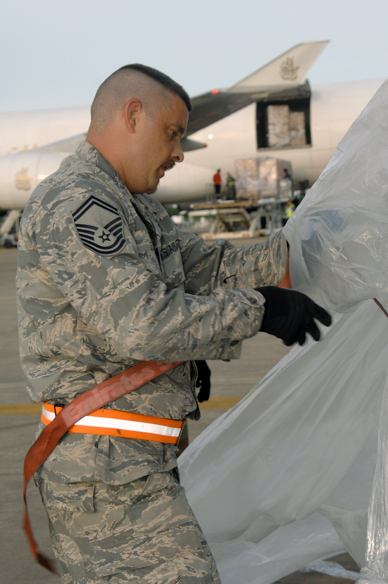Senior Master Sgt. Gregory Stone removes plastic lining from a pallet of supplies offloaded from a Boeing 747 commercial airplane May 16 at Utapao Thai Royal Navy Air Base, Thailand.  The humanitarian aid supplies are to be delivered to Burma.  Sergeant Stone is from the 36th Contingency Response Group at Andersen Air Force Base, Guam. (U.S. Air Force photo/Senior Airman Sonya Croston)