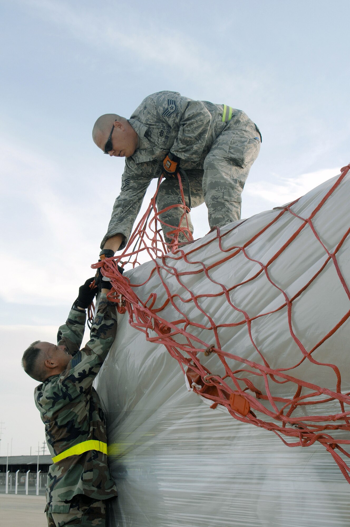 Tech. Sgt. John Kortez (below) and Staff Sgt. Randy Afshar remove cargo netting from a pallet offloaded from a Boeing 747 commercial airplane May 16 at Utapao Thai Royal Navy Air Base, Thailand.  The humanitarian aid supplies are to be delivered to Burma. Sergeant Kortez is from the 36th Contingency Response Squadron and Sergeant Afshar is from the 554th RED HORSE Squadron, both from Andersen Air Force Base, Guam. (U.S. Air Force photo/Senior Airman Sonya Croston)