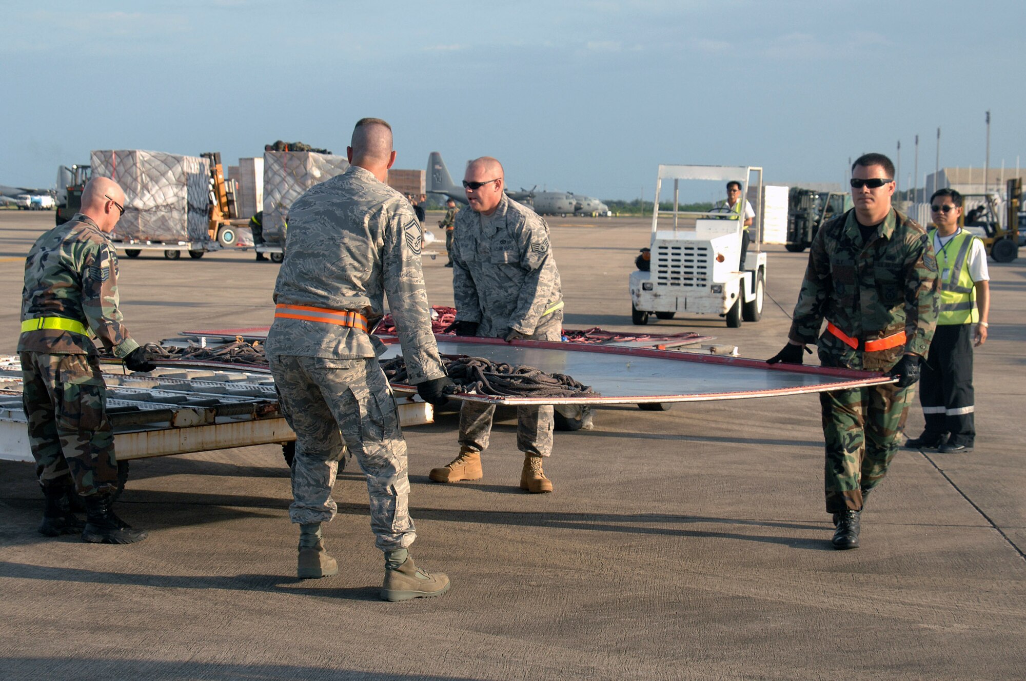 Airmen from Andersen Air Force Base, Guam, remove a cookie sheet being used for the transfer of 169,000 pounds of humanitarian aid supplies for delivery to Burma from a Boeing 747 commercial airplane May 16 at Utapao Thai Royal Navy Air Base, Thailand. (U.S. Air Force photo/Senior Airman Sonya Croston)