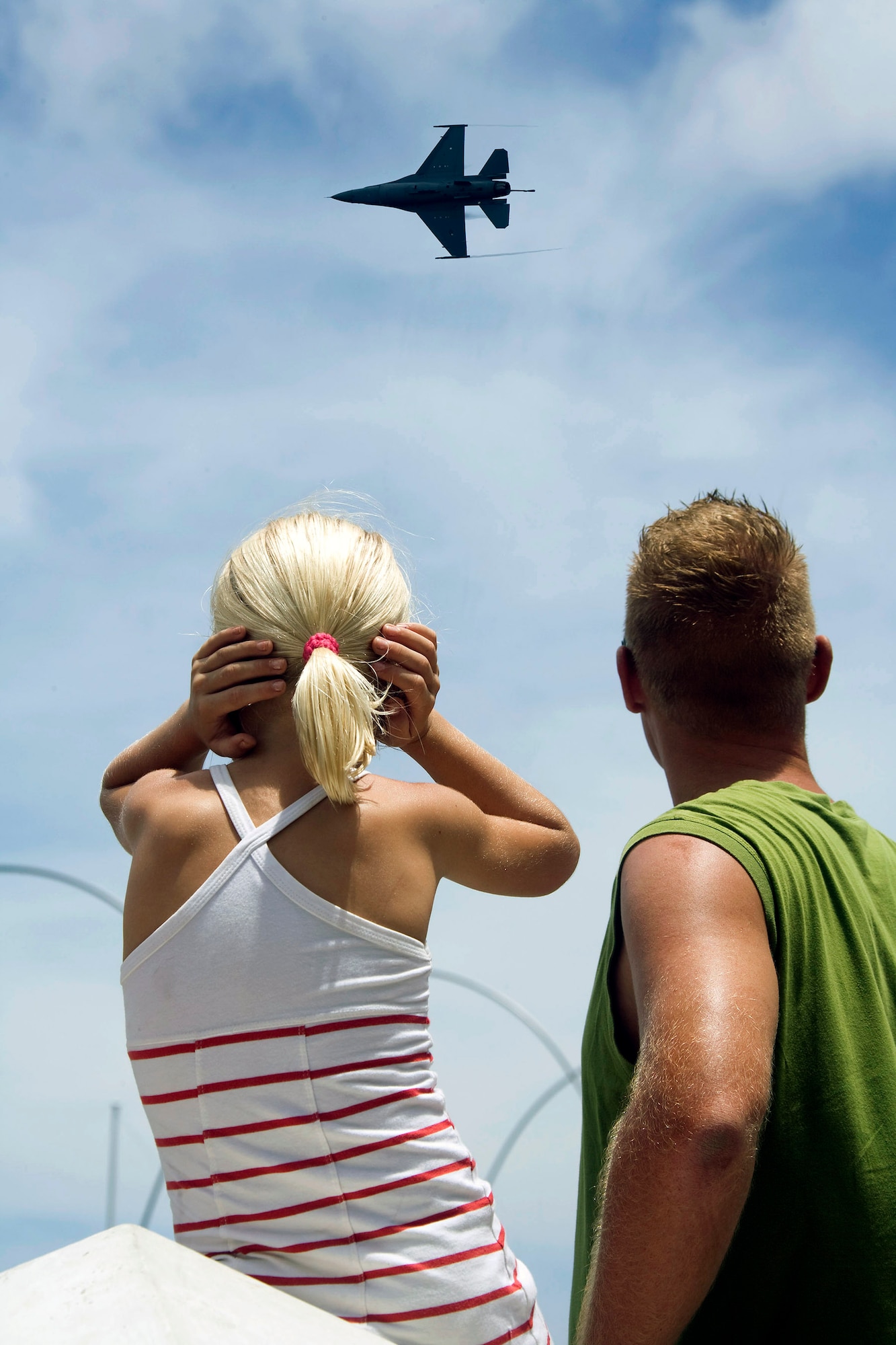 A local child covers her ears as an F-16 Fighting Falcon, flown by Capt. George Clifford of the Viper East F-16 demonstration team, flies over Curacao, Netherlands Antilles.  The Viper East team, from Shaw Air Force Base, S.C., joined officials from Air Forces Southern headquarters at Davis-Monthan AFB, Ariz., to augment "Dutch Navy Days," a celebration put on every three years by the Dutch military to honor their naval heritage and partnership with the people of Curacao. (Courtesy photo/Peter Bijpost)