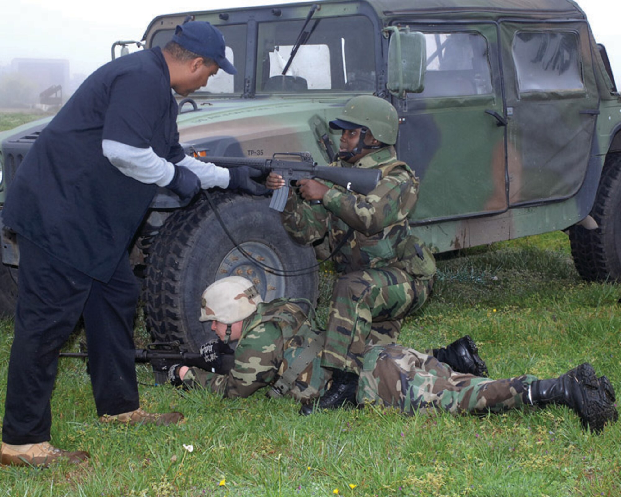 LANGLEY AIR FORCE BASE, Va. -- Mr. William Rupert, 1st Security Forces Squadron expeditionary combat skills instructor, shows Senior Airmen Kayann Kinkle (kneeling) and Charles Hunt how to work as partners, taking tactical deployment positions while exiting a Humvee here April 10. Airman Kinkle is a supply specialist with the new 735th Supply Chain Management Group, and Airman Hunt is a firefighter with the Langley Fire Department. Combat Skills Training is a basic three-day course for deploying personnel where Airmen who are normally in noncombatant roles learn to shoot, move and communicate. (U.S. Air Force photo/Master Sgt.Carlos J. Claudio)