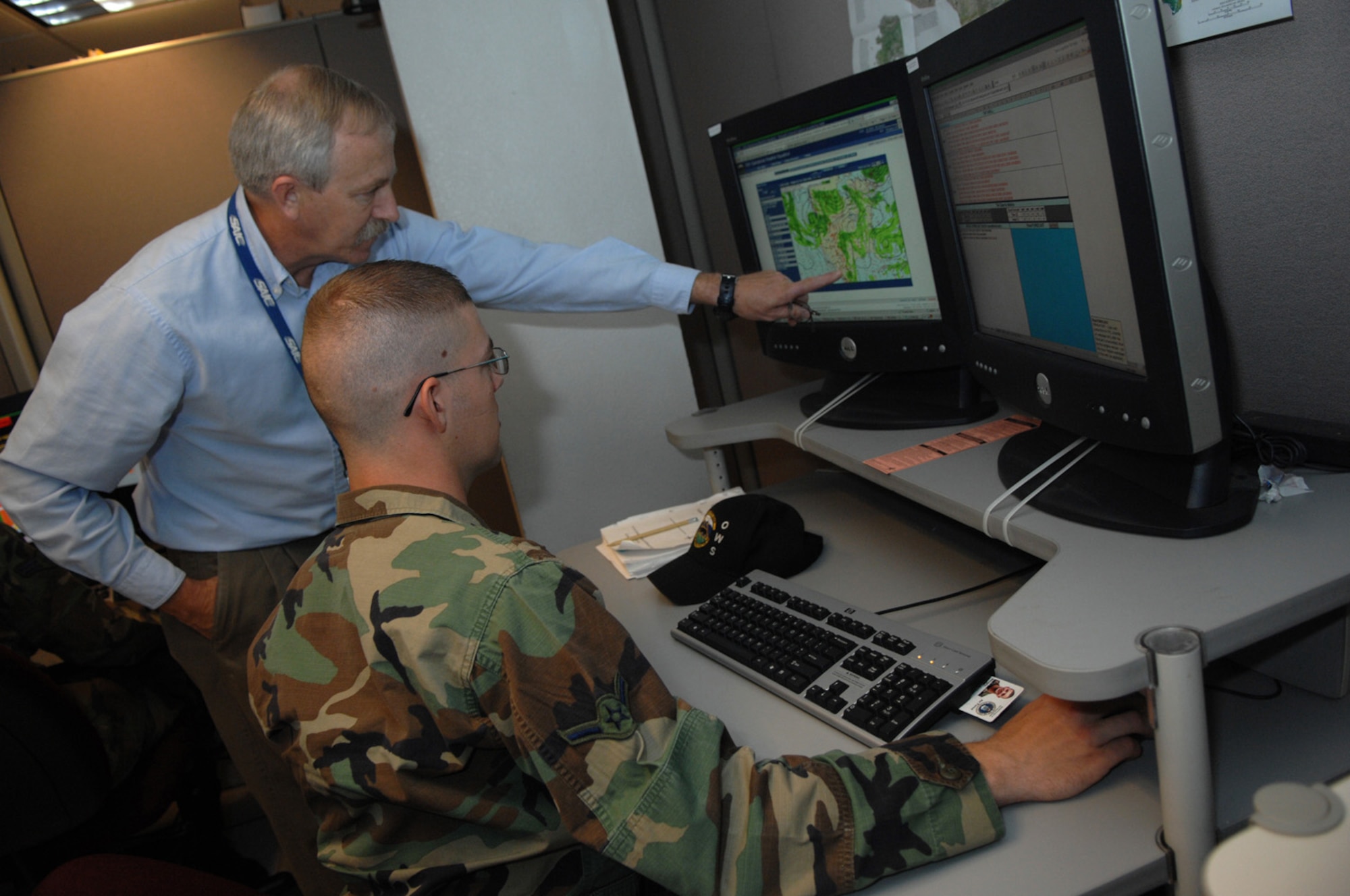 Tim Smith, left, instructs Airman William Mingey on the proper procedures for forecasting interpreting graphic output or precipitation from computer weather modules.  All newly assigned Airmen receive extensive training to prepare them for the unique forecast challenges throughout the western United States.  Mr. Smith and Airman Mingey are members of the 25th Operational Weather Squadron.  (U.S. Air Force photo by Senior Airman Alesia Goosic)