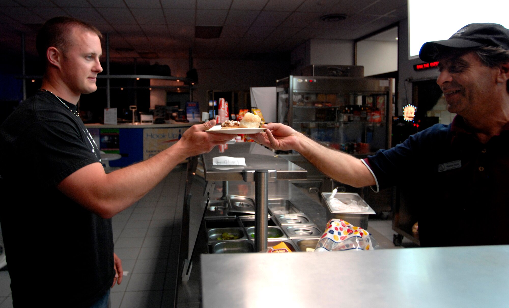AVIANO AIR BASE, Italy --  Maurizio Nuzzo hands Justin Mahr food he ordered at the Ten Pin Inn bowling center grill May 17.  The grill is open until 10 p.m. during cosmic bowling  (U.S. Air Force photo/Airman 1st Class Ashley Wood)